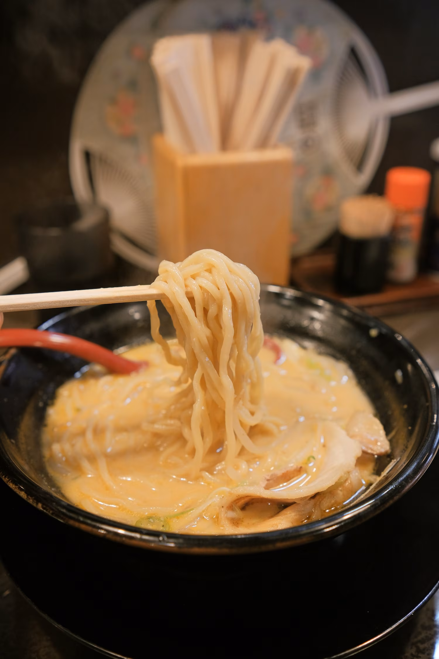 Bacchette che sollevano i noodles da una ciotola di ramen